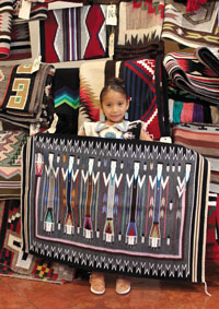 Adorable little girl holding up a Navajo Rug